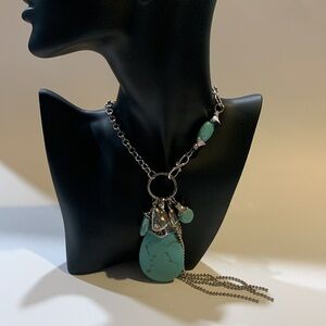 Silver tone and turquoise necklace with oversized pendant and charms.